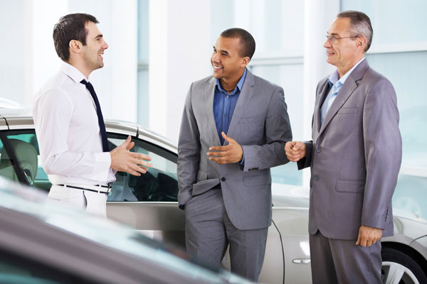 customer speaking with two salesmen in a car dealership