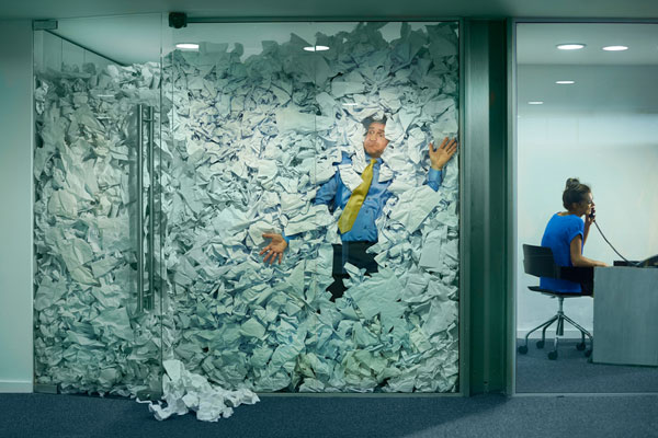 Man in office drowning in paper