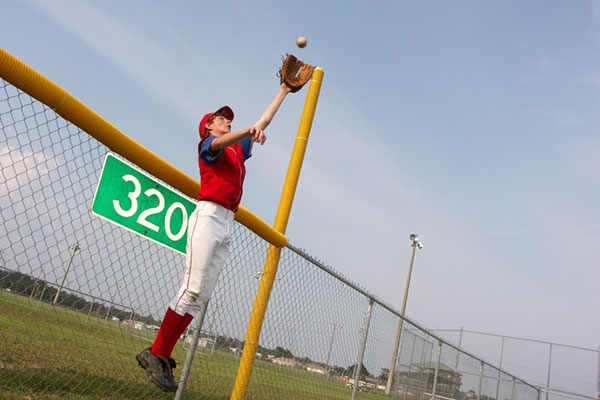 Boy catching baseball over the fence
