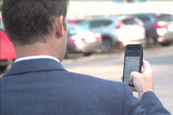 Man holding mobile phone on vehicle lot