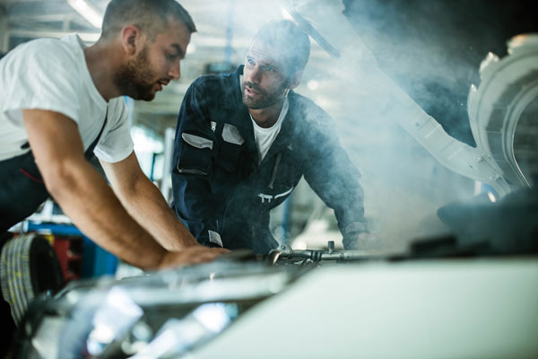 Two technicians working on smoking engine