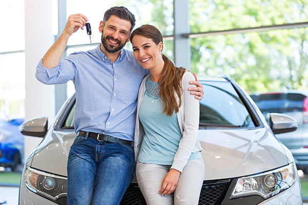 Happy couple holding keys to new car