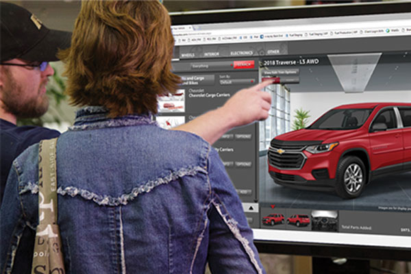 Couple working on a large monitor to customize their vehicle