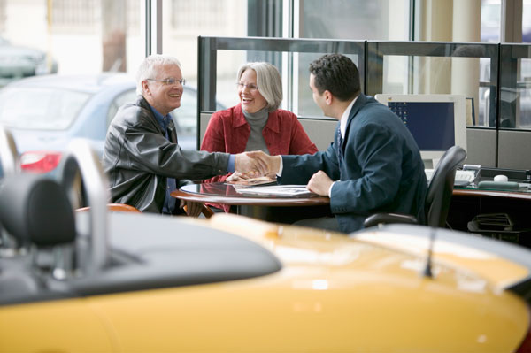 Couple shaking hands with salesperson at desk