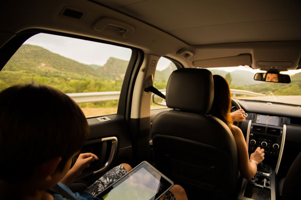 Woman driving vehicle with young boy in backseat