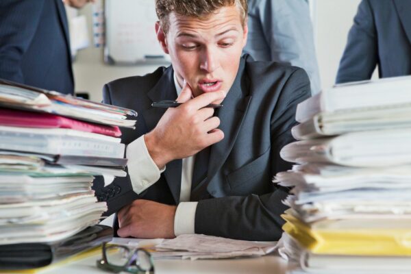 Man looking overwhelmed, reviewing paperwork