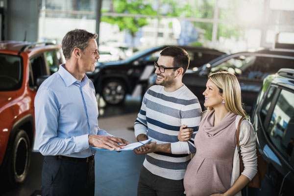 Pregnant woman and her husband talking to a salesperson.