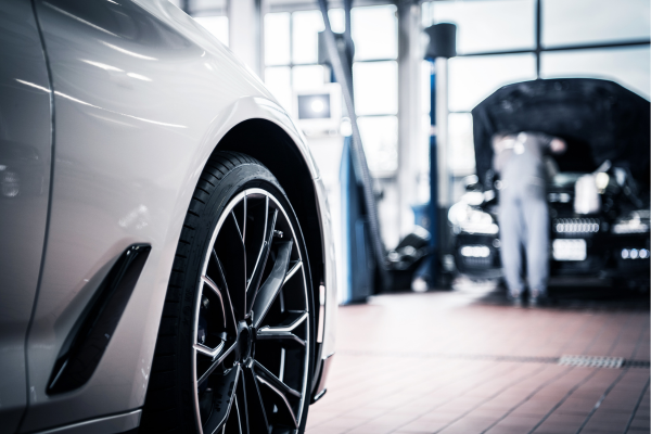 Car in foreground with technician in background working on a car