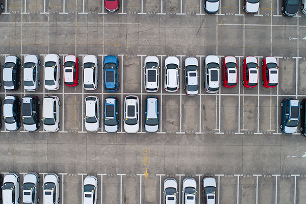 aerial shot of a parking lot; some of the parking spots are filled with vehicles and some of them are empty