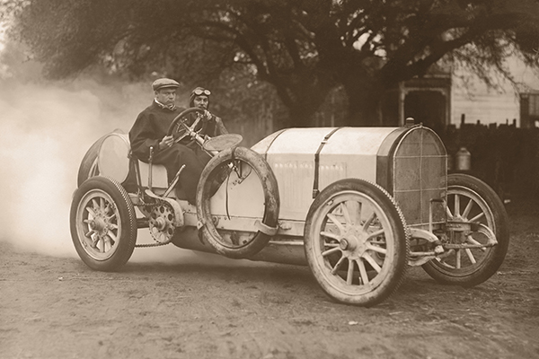 old black and white image of a man driving a car
