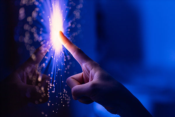 hand touching a screen with a spark of light at the center