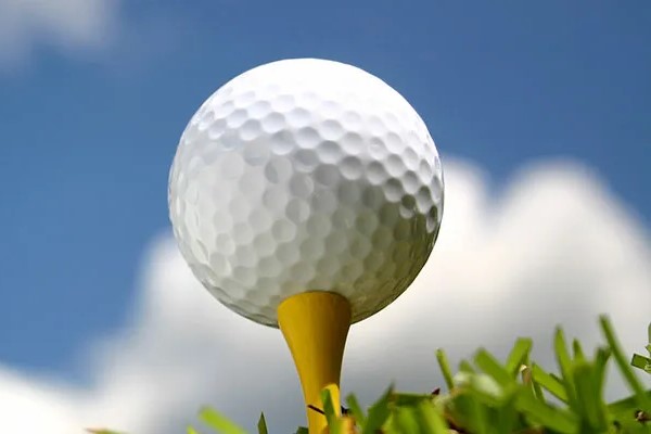 Golf ball resting on yellow golf tee.