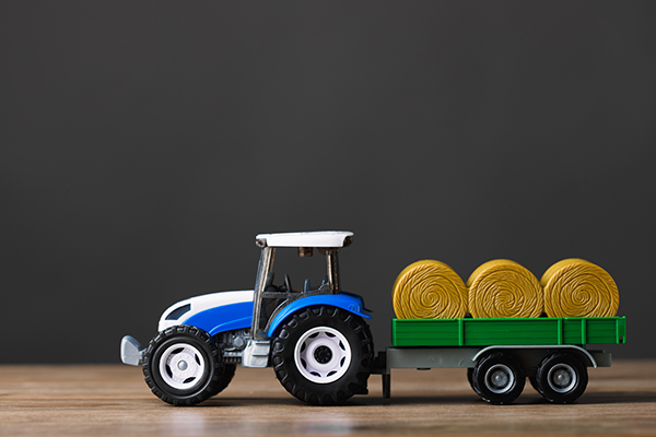 Toy tractor pulling a load of baled hay.